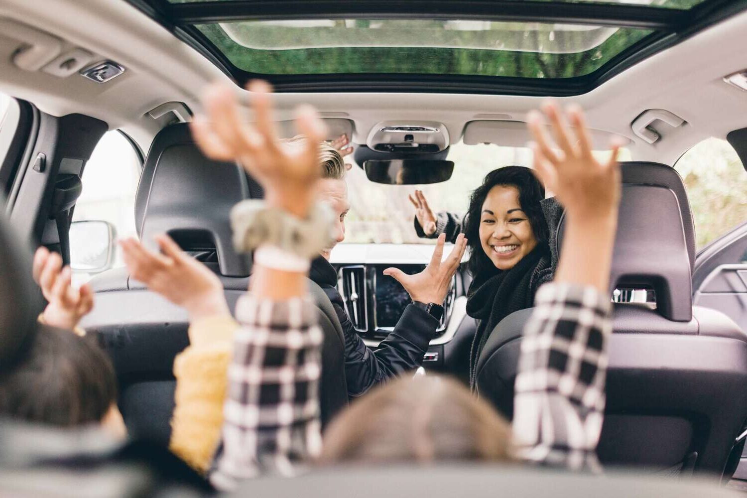 kids playing in the car while mom turns around and smiles at them