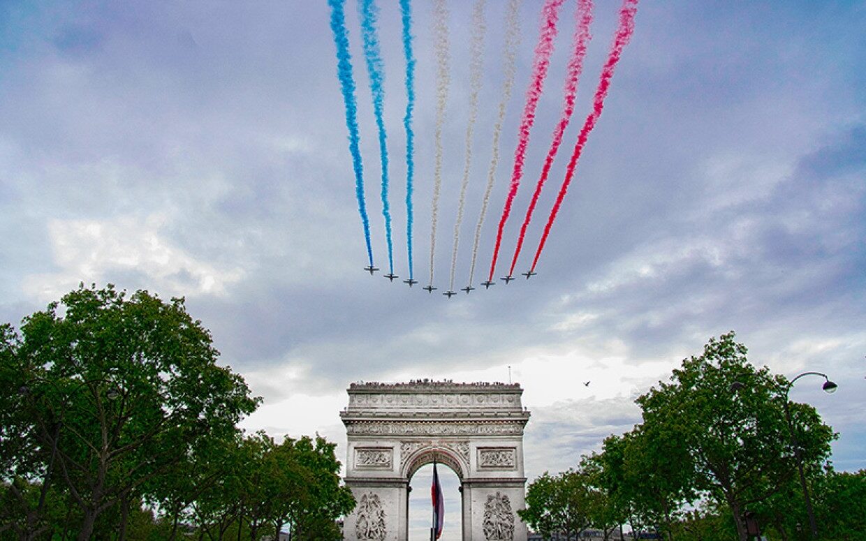 9 jets emitting with blue, white, and red smoke over a monument on Bastille Day in France