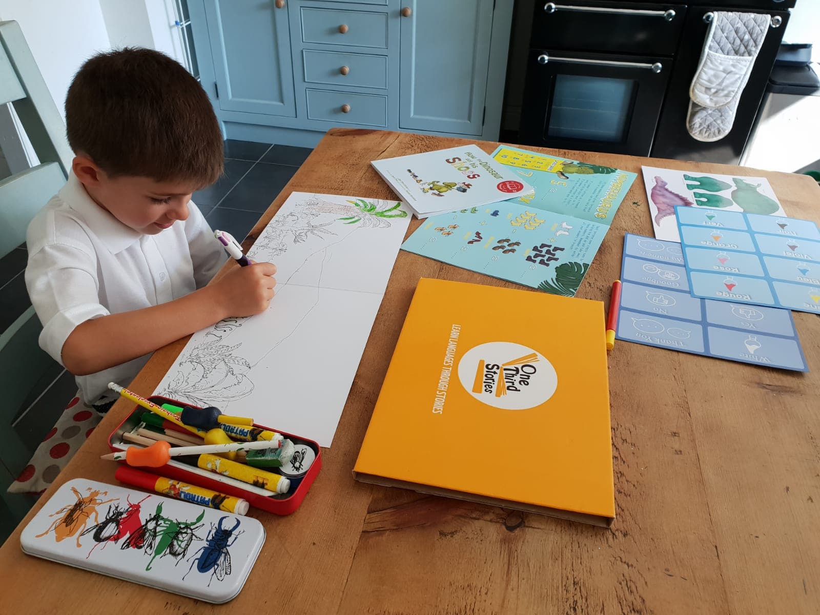 child at table with One Third Stories activity sheets and crayons