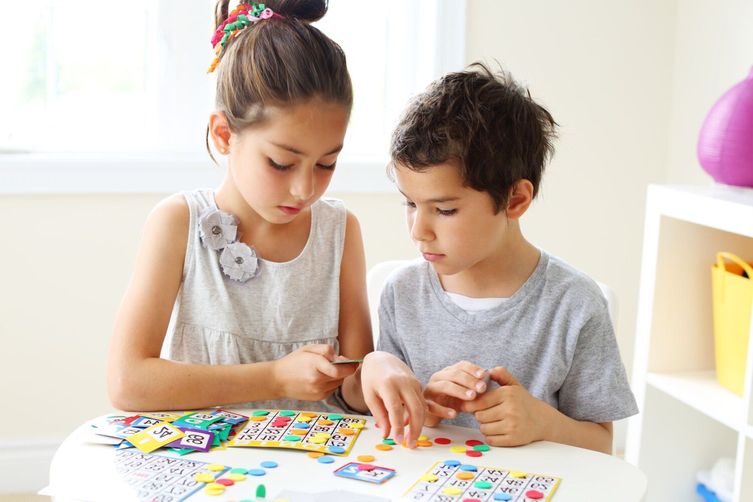 two children at a table playing bingo