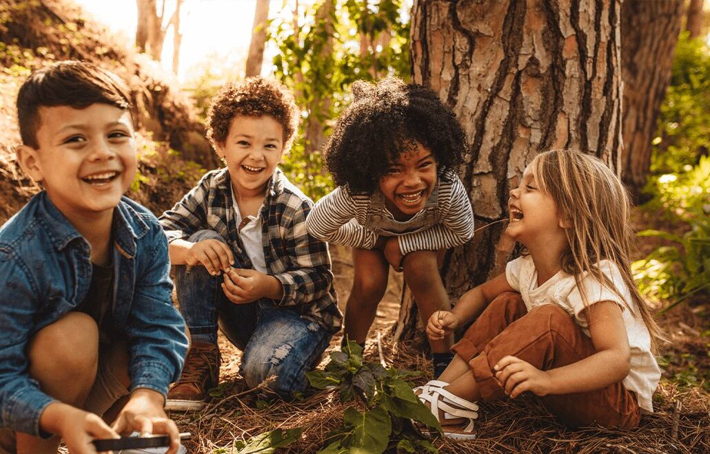 children outside sitting on the ground by a tree